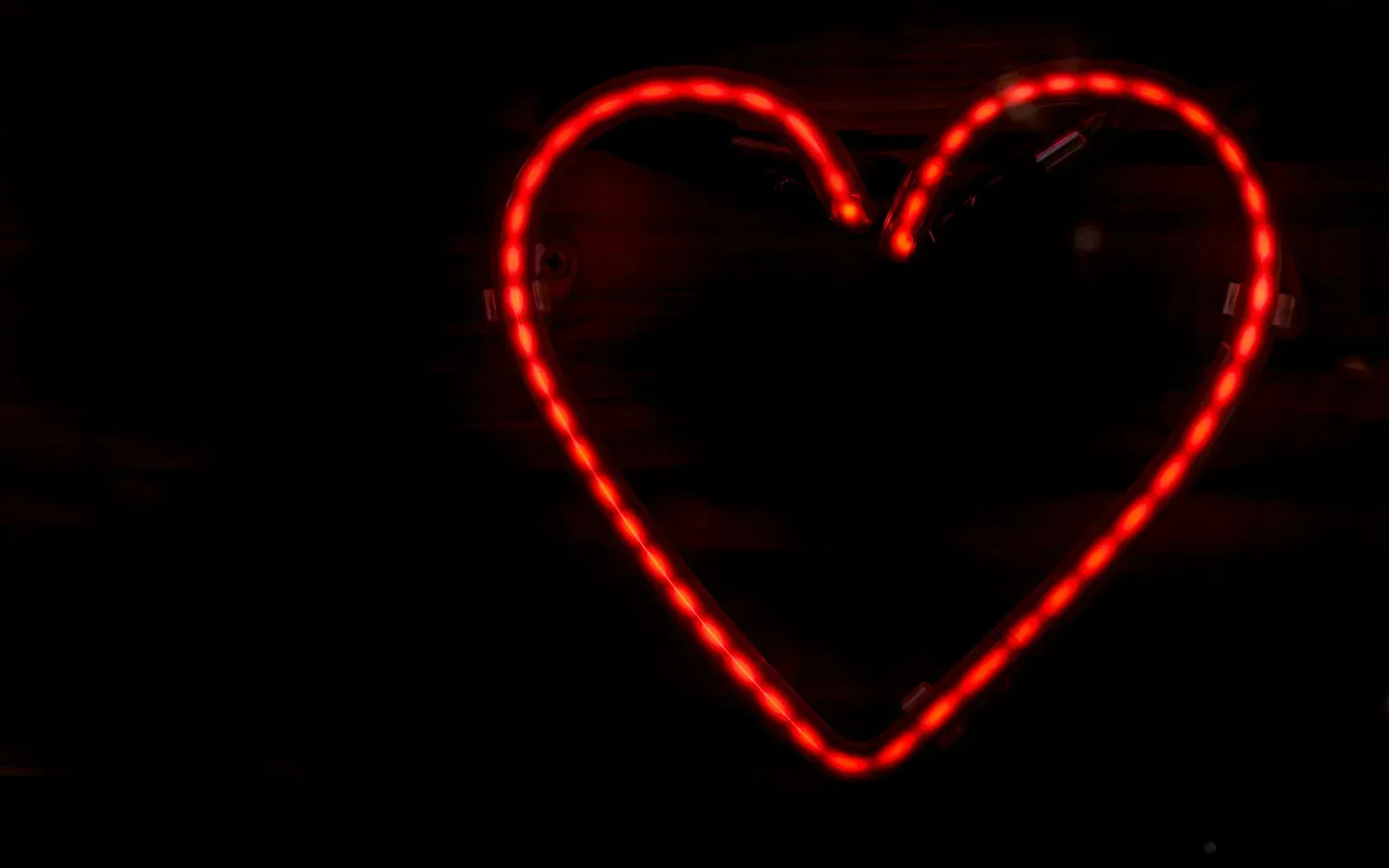 Rot leuchtendes Neon-Herz vor dunklem Hintergrund – Badoo Erfahrungen mit der Dating-App