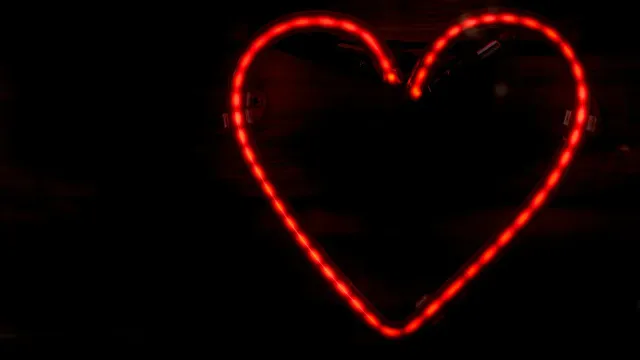 Rot leuchtendes Neon-Herz vor dunklem Hintergrund – Badoo Erfahrungen mit der Dating-App